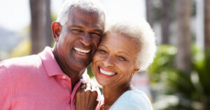 A mature couple embraces and smiles brightly after implant treatment