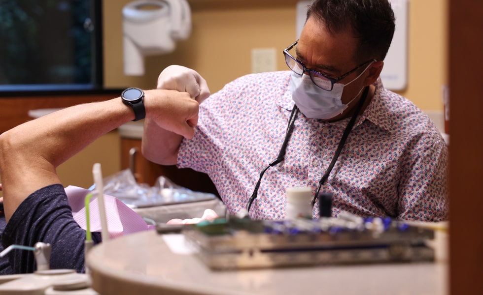 Dr. Sherman shares a fist bump with a patient in the dental chair, creating a warm and friendly moment