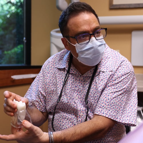 Dr. Ron Sherman in a medical mask holding dental prototype